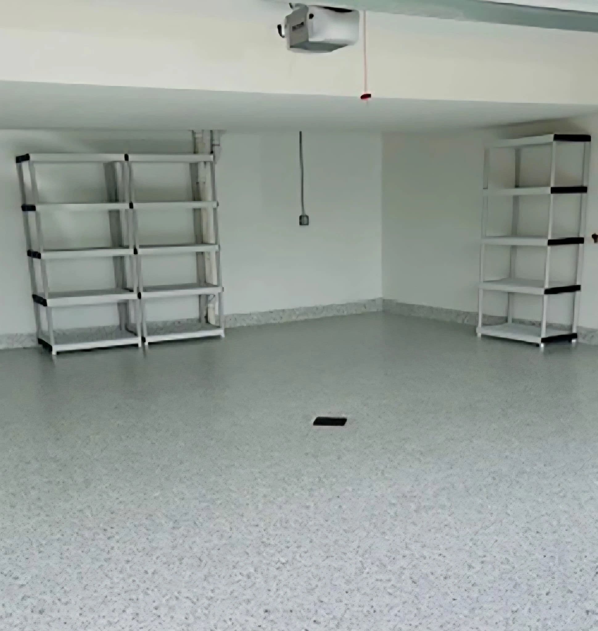 Fertige Garage mit hellgrauem Chip-Boden und weißen Regalen